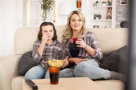 mother and daughter watching a movie sitting on the couch stock image image of home living