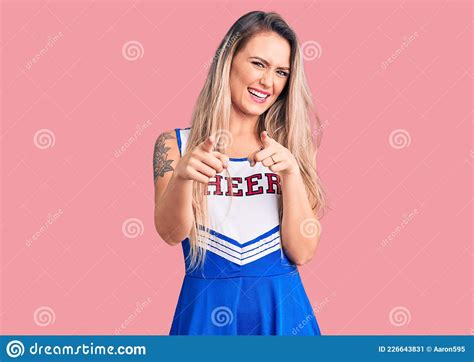 Young Beautiful Blonde Woman Wearing Cheerleader Uniform Pointing Fingers To Camera With Happy