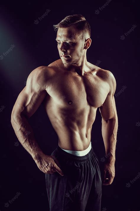 Bodybuilder Posant Fitness Homme Musclé Sur Mur Sombre Photo Premium