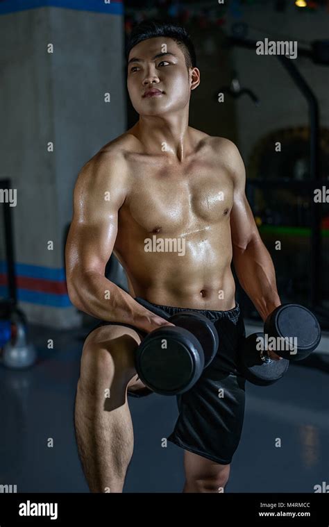 Handsome Young Athletic Chinese Man Doing Exercises With Dumbbells In