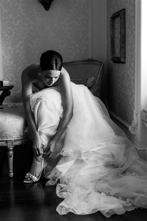 A Woman In A Wedding Dress Tying Her Shoes
