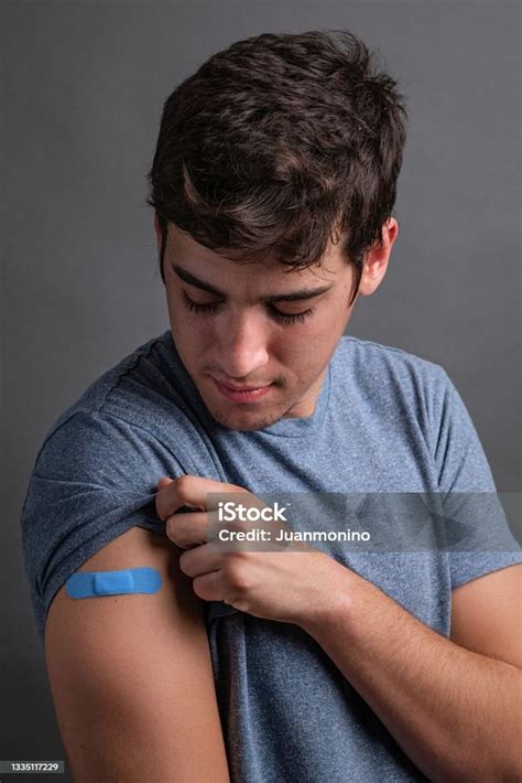 Photo Libre De Droit De Jeune Homme Posant En Regardant Son Pansement De Vaccination Dans Son