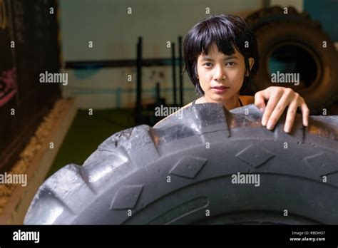 Asian Fitness Woman Pushing And Flipping Wheel Truck Tire At Gym Stock