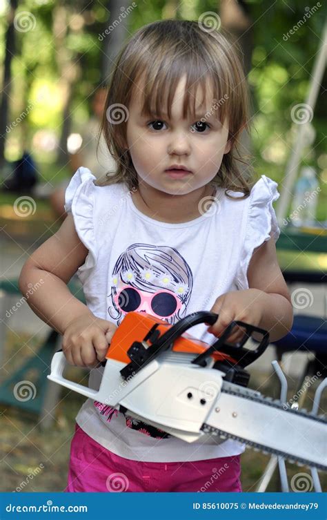 Baby Girl Holding And Working With An Electric Saw A Chainsaw Stock