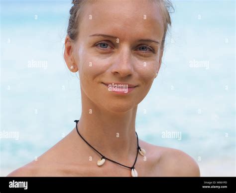 portrait of a beautiful slim girl wearing a bikini puts on her face sunscreen on the beach near