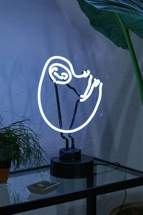 A Neon Sign That Is Sitting On Top Of A Glass Table Next To A Potted Plant