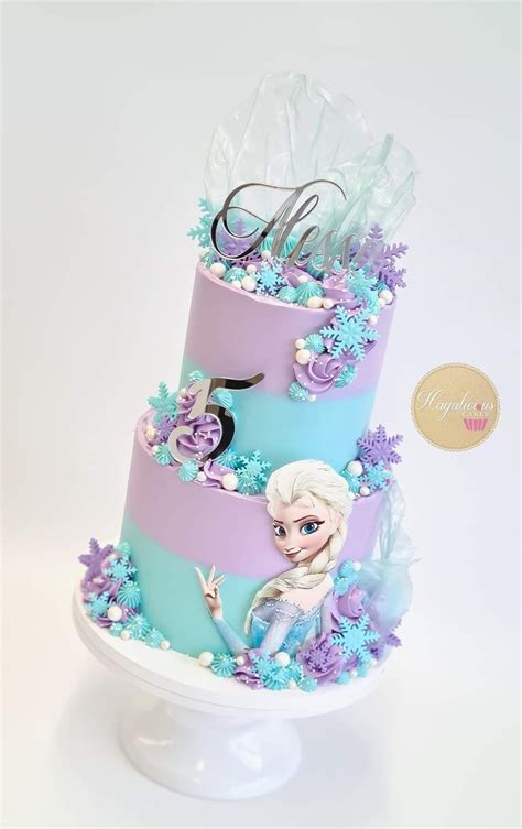 A Three Tiered Cake Decorated With Frozen Princesses And Snowflakes On Top