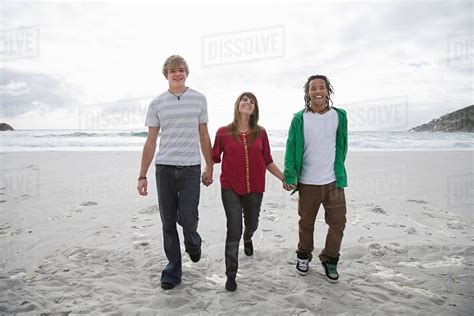 Three People Walking On Beach Holding Hands Stock Photo Dissolve