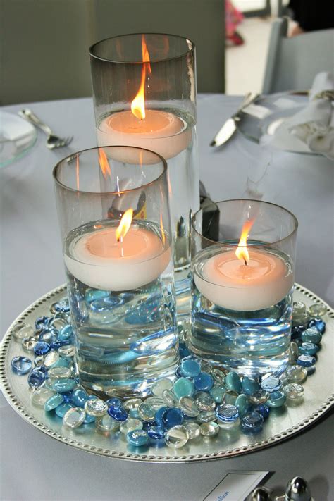 3 Glass Cylinder Wedding Centerpiece With Floating Candles Surrounded By Blue And Clear Glass