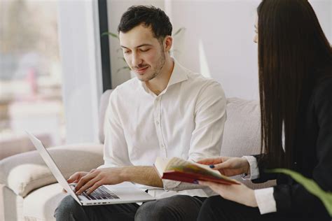 Smiling Male Coworker With Laptop And Female Colleague With Book · Free