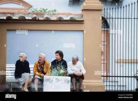 Four Elderly Italian Ladies Sitting On A Public Bench Having A