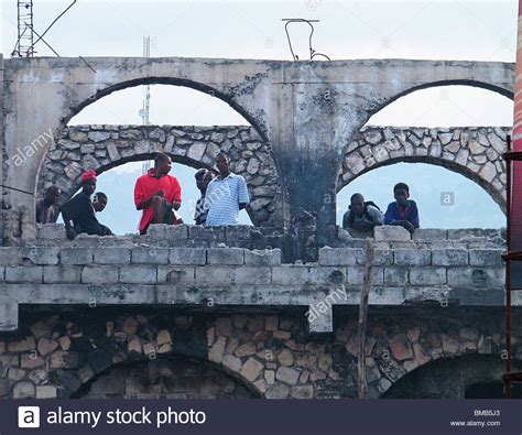 Men Look Out From A Damaged Building In Port Au Prince After The Haiti