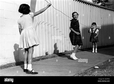 mexico in the 1960s three girls are playing in the street with a skipping rope jumping rope