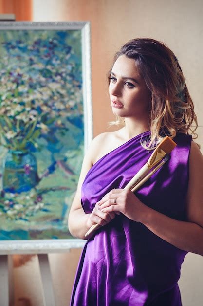 Premium Photo Model Girl In A Blue Dress In An Art Workshop With Brushes A Palette And Paintings