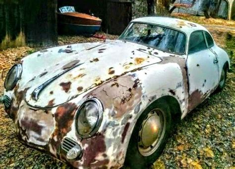 An Old Rusted Out Car Is Parked On The Ground In Front Of A Tree