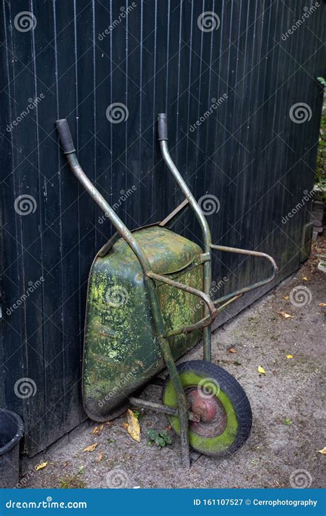 Old And Rusty Wheelbarrows Rest Against Wall Of Farm Barn Royalty Free