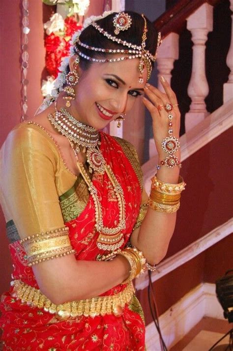 A Woman In A Red And Gold Sari Posing For The Camera With Her Hand On Her Head