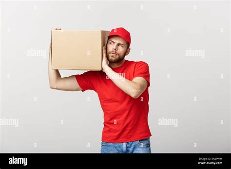 delivery concept portrait of curious caucasian handsome delivery man listen inside a box