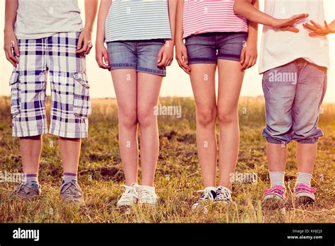 Photo Of Four Kids Legs Standing At The Summer Sunny Field Wearing