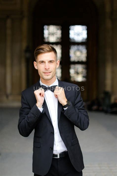 Young Caucaisian Man Standing And Posing Wearing Black Suit And Bow