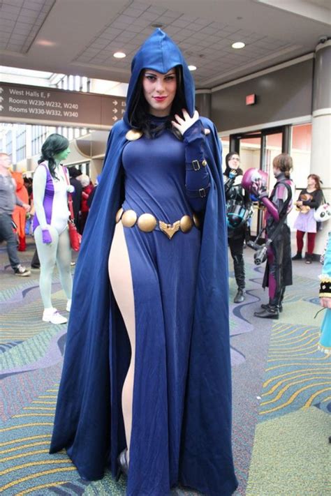A Woman Dressed In A Blue Cape And Bodysuit Posing For The Camera With Her Hands On Her Hips