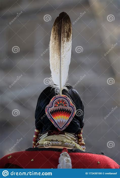 Native American Indian Woman In A Traditional Outfit With An Eagle Feather In Her Hair At A