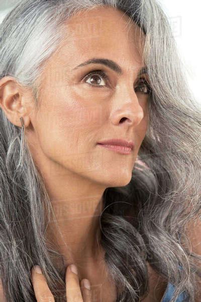 Close Up Of A Middle Aged Woman With Gray Hair Looking Up Off Camera And Brushing Away Her Hair