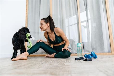 White Brunette Woman Smiling And Playing With Her Dog While Working Out