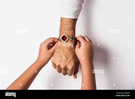 Close Up Top View Of Female Hands Tying Colorful Rakhi On Her Brothers Hand Isolated On White