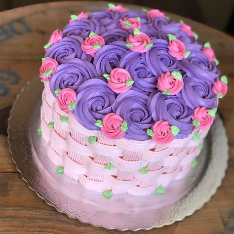 A Cake With Purple Frosting And Pink Flowers On Top Is Sitting On A Plate