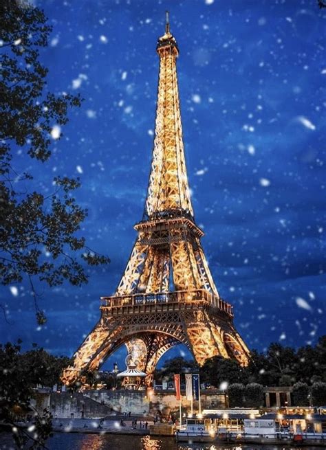 The Eiffel Tower Lit Up At Night With Snow Falling On It And People