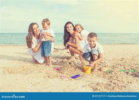 Dos Madres Jovenes Y Sus Niños Que Se Divierten En La Playa Foto De