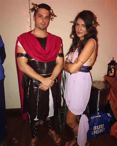 A Man And Woman Dressed Up In Roman Costumes Standing Next To Each