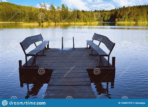 Dock Or Pier On Lake In Summer Day Empty Footbridge With Two Benches