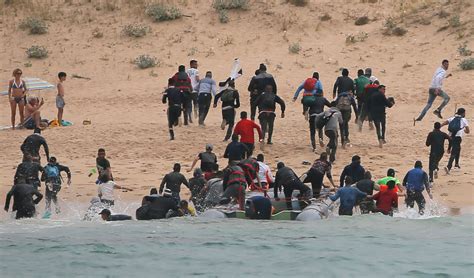 Migrants land on Spanish beach, flee as tourists look on ...