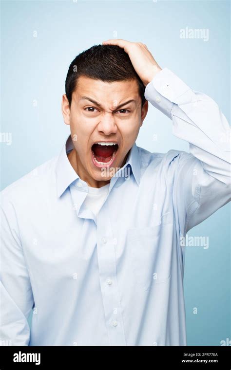 Shot Of A Young Man Pulling His Hair In Frustration Against A Studio