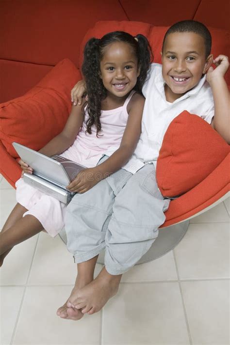 brother and sister in chair with dvd player picture image 13584361