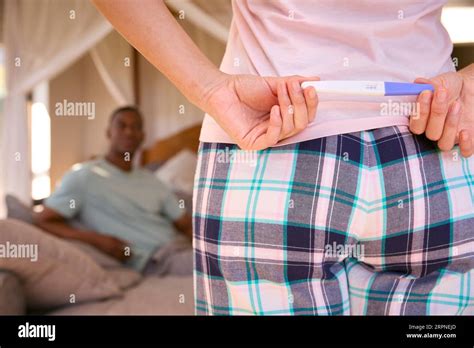 Woman In Bedroom Hiding Positive Pregnancy Test Behind Back To Surprise