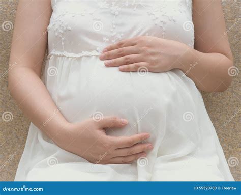 Young Pregnant Woman Putting Hands On Belly Feeling Her Baby Stock
