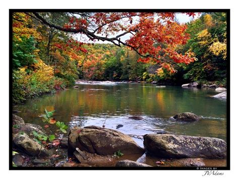 A River Surrounded By Lots Of Rocks And Trees With Fall Colors In The