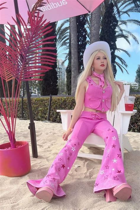 a barbie doll sitting on a beach chair with an umbrella over her head and palm trees in the
