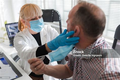 Male Patient Having Tonsils And Throat Checked By A Female Doctor Stock