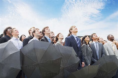 Crowd Of Business People With Umbrellas Looking Up At Sky Stock Photo
