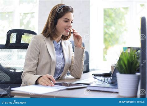 Cheerful Female Manager Sitting At Office Desk And Performing Corporate
