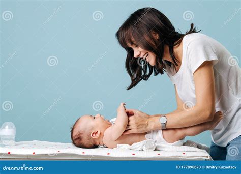 Young Beautiful Mom Changes Baby S Diaper And Smiles At Him Stock Image
