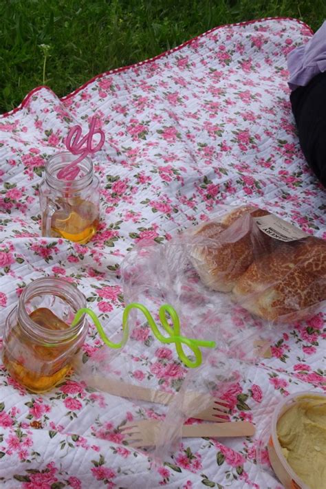 A Picnic Blanket On The Grass With Some Food And Honey In Glass Jars