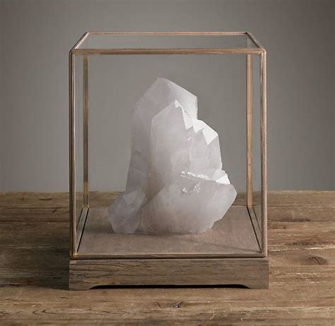 A White Rock In A Glass Box On A Wooden Table With A Gray Wall Behind It