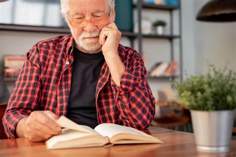 Premium Photo Senior Bearded Man Sitting At Table Reading A Book