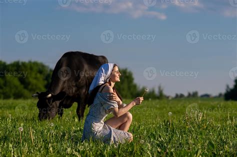 Une Jeune Fille Dans Une Vache Pâturage Est Séance Avec Sa Yeux Fermé Dans Une Robe 20075436