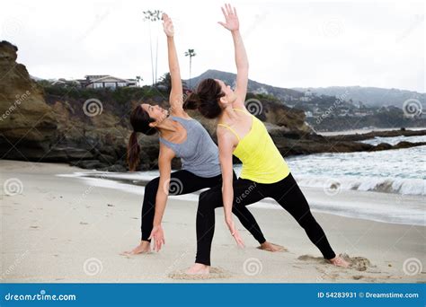 Dos Mujeres Hermosas Que Practican Yoga En La Playa Imagen De Archivo